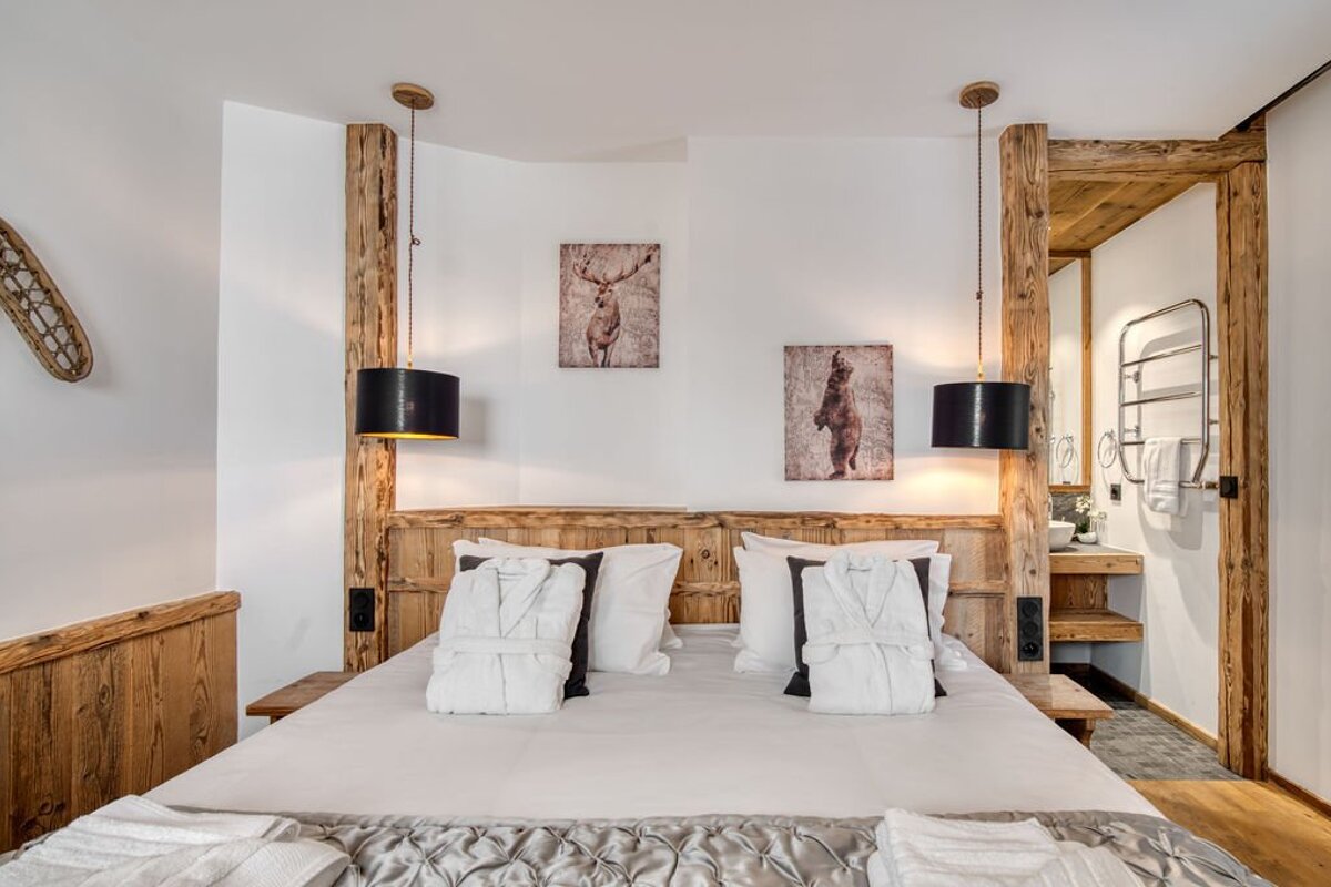 A bedroom with a bed and two paintings on the wall