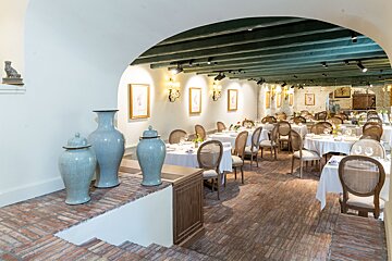 A restaurant with tables and chairs and vases on the floor