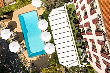 An aerial view of a hotel with a large pool and umbrellas