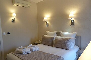 A bedroom with a bed and two lamps on the wall