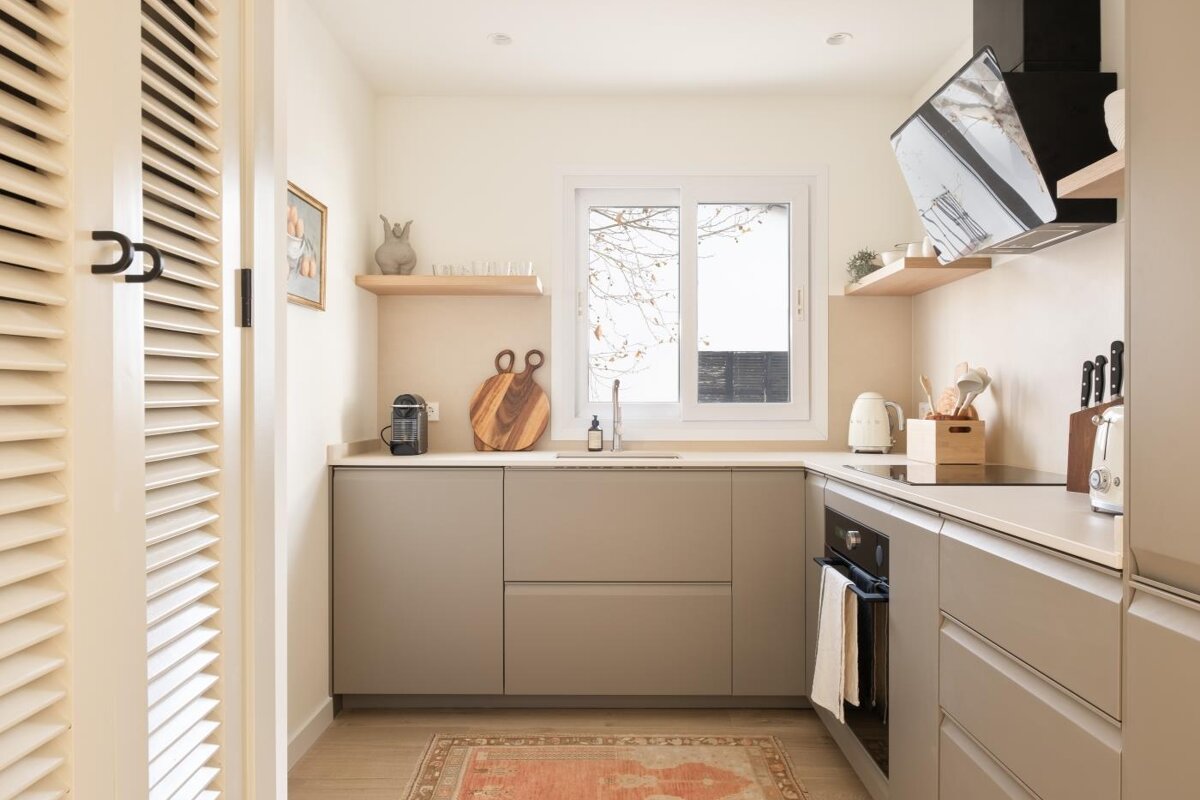 A kitchen with beige cabinets and a rug on the floor