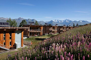 A row of houses on a hill with mountains in the background