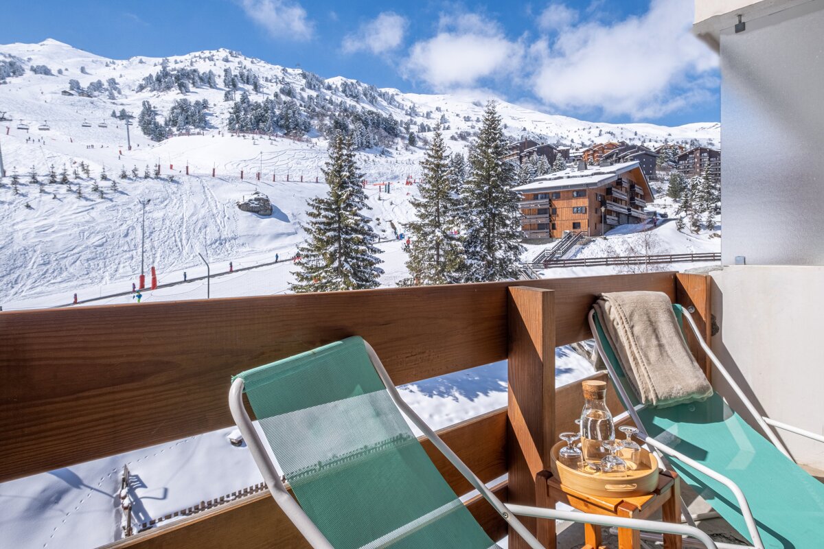 Two chairs on a balcony overlooking a snowy mountain