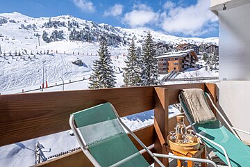 Two chairs on a balcony overlooking a snowy mountain