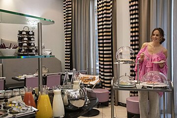A woman in a pink top is standing in front of a buffet table