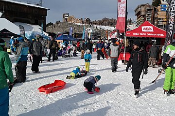 A group of people are gathered around a tent that says high tech good times