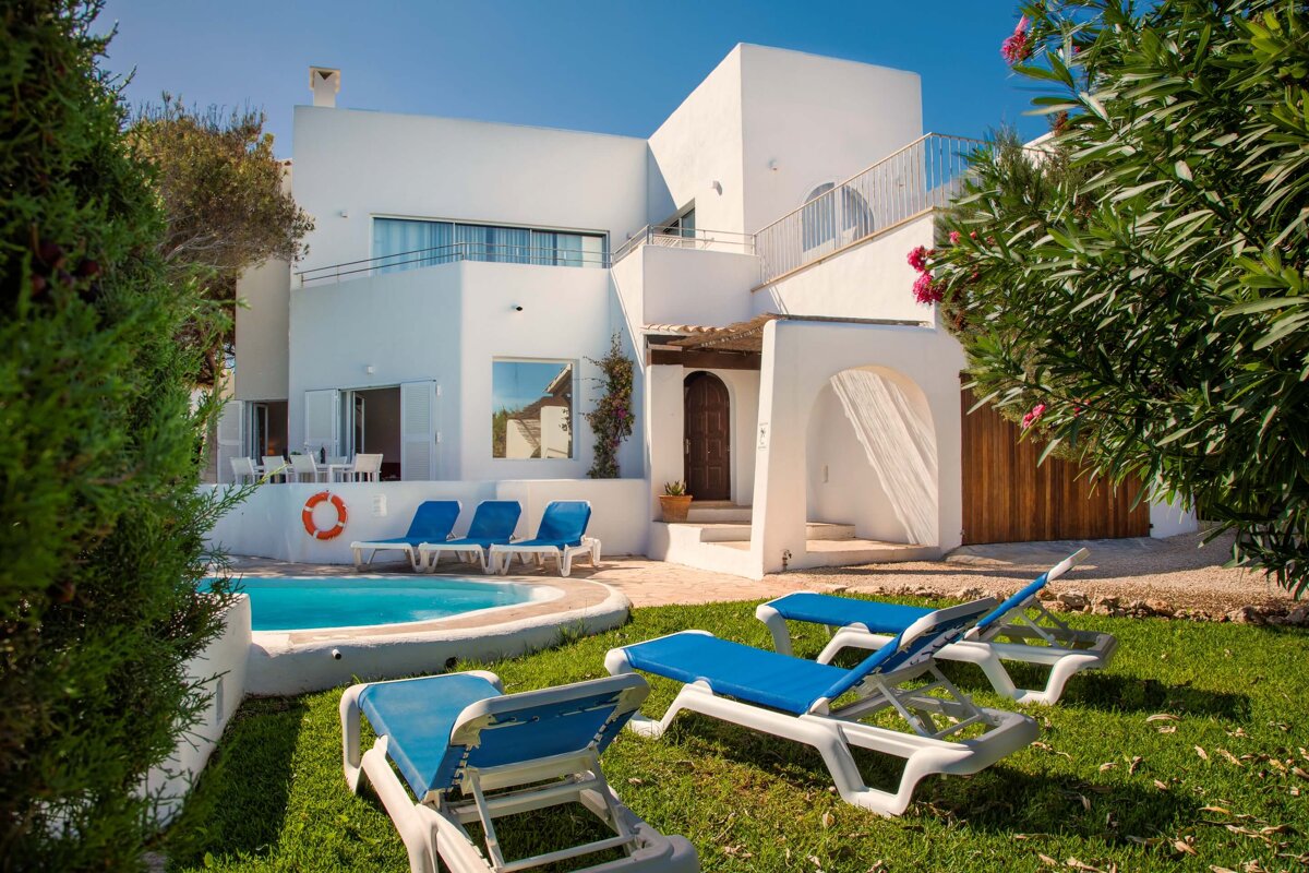 A white house with a swimming pool in front of it