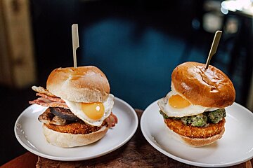 Two sandwiches on white plates with toothpicks in them
