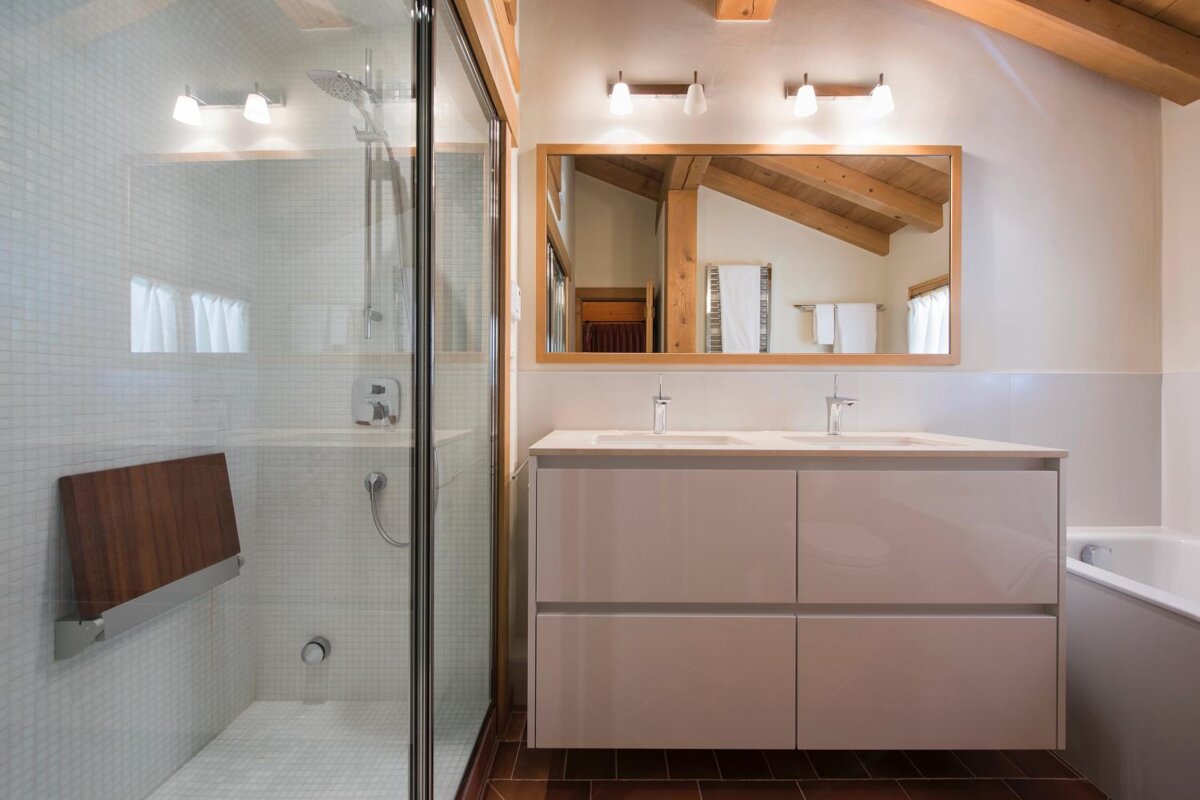 A bathroom with two sinks and a walk in shower