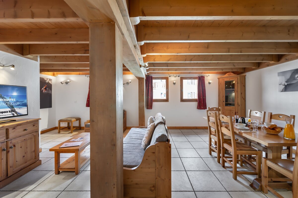 A living room with a couch and a table and chairs and a flat screen tv
