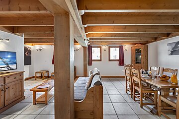 A living room with a couch and a table and chairs and a flat screen tv