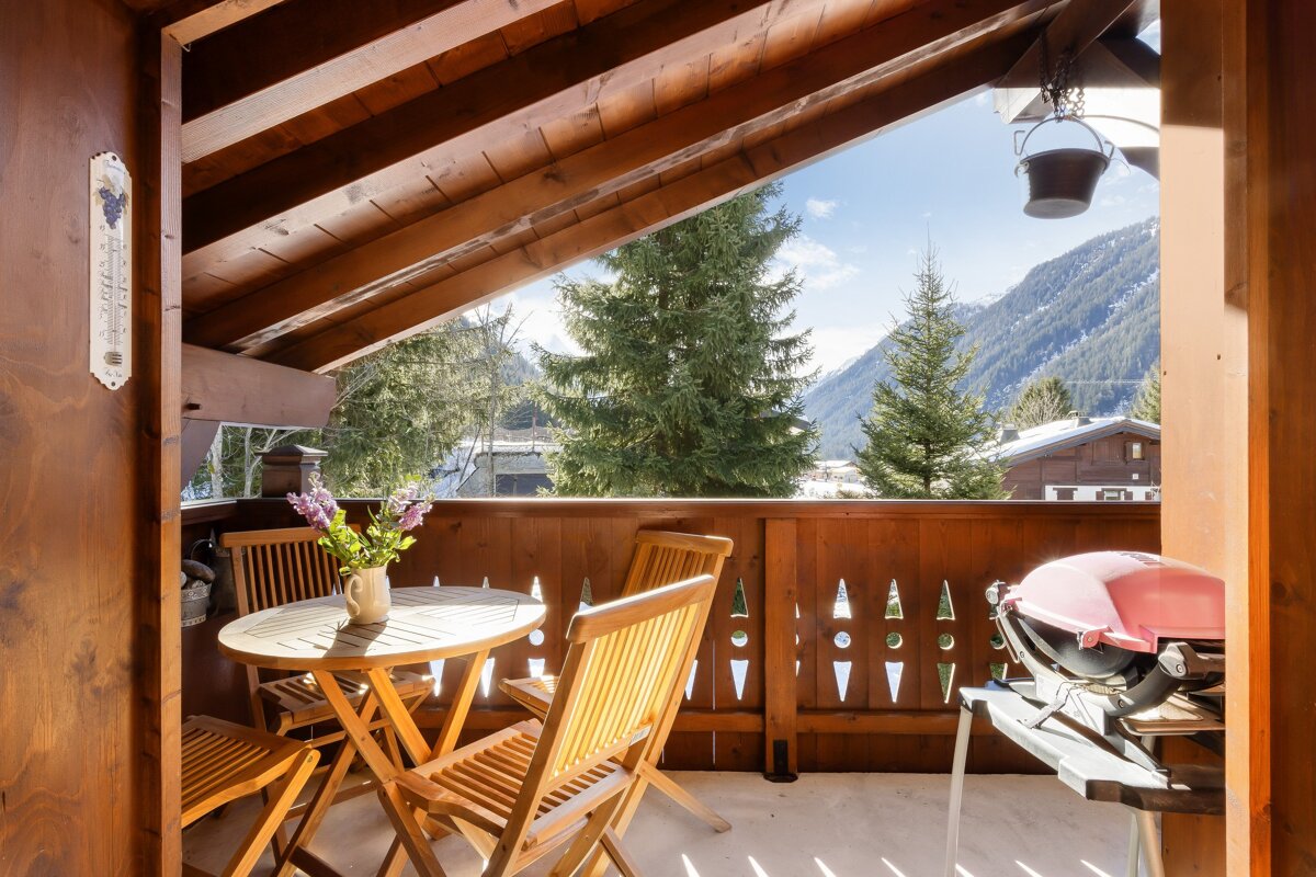 A balcony with a table and chairs and a thermometer on the wall
