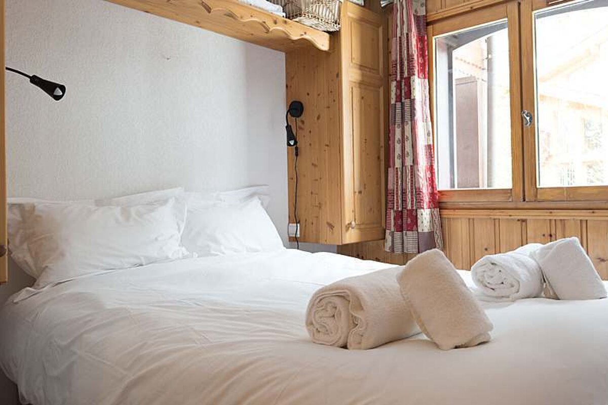 A bed with white sheets and pillows and towels on it