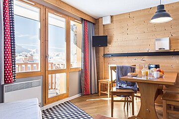 A living room with a table and chairs and a television