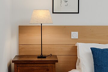 A nightstand with a lamp and a picture on the wall above it