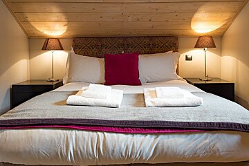 A bed with white sheets and a pink pillow