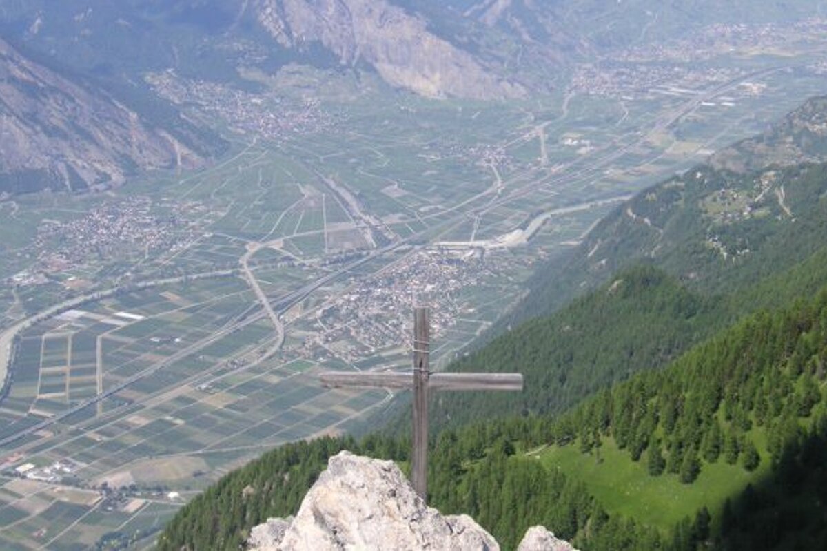 A cross on top of a mountain overlooking a valley