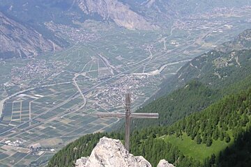 A cross on top of a mountain overlooking a valley
