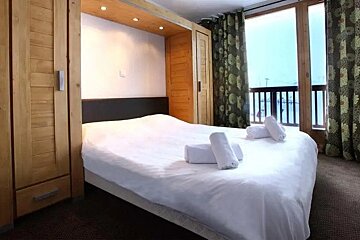 A bedroom with a large bed and a balcony