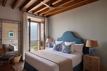 A bedroom with a blue headboard and white sheets
