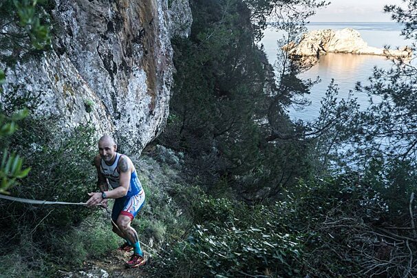 A man with a tattoo on his arm is running down a trail