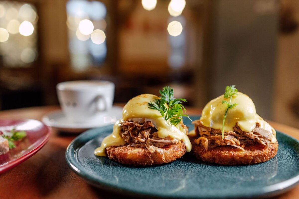 A plate of food with a cup of coffee in the background