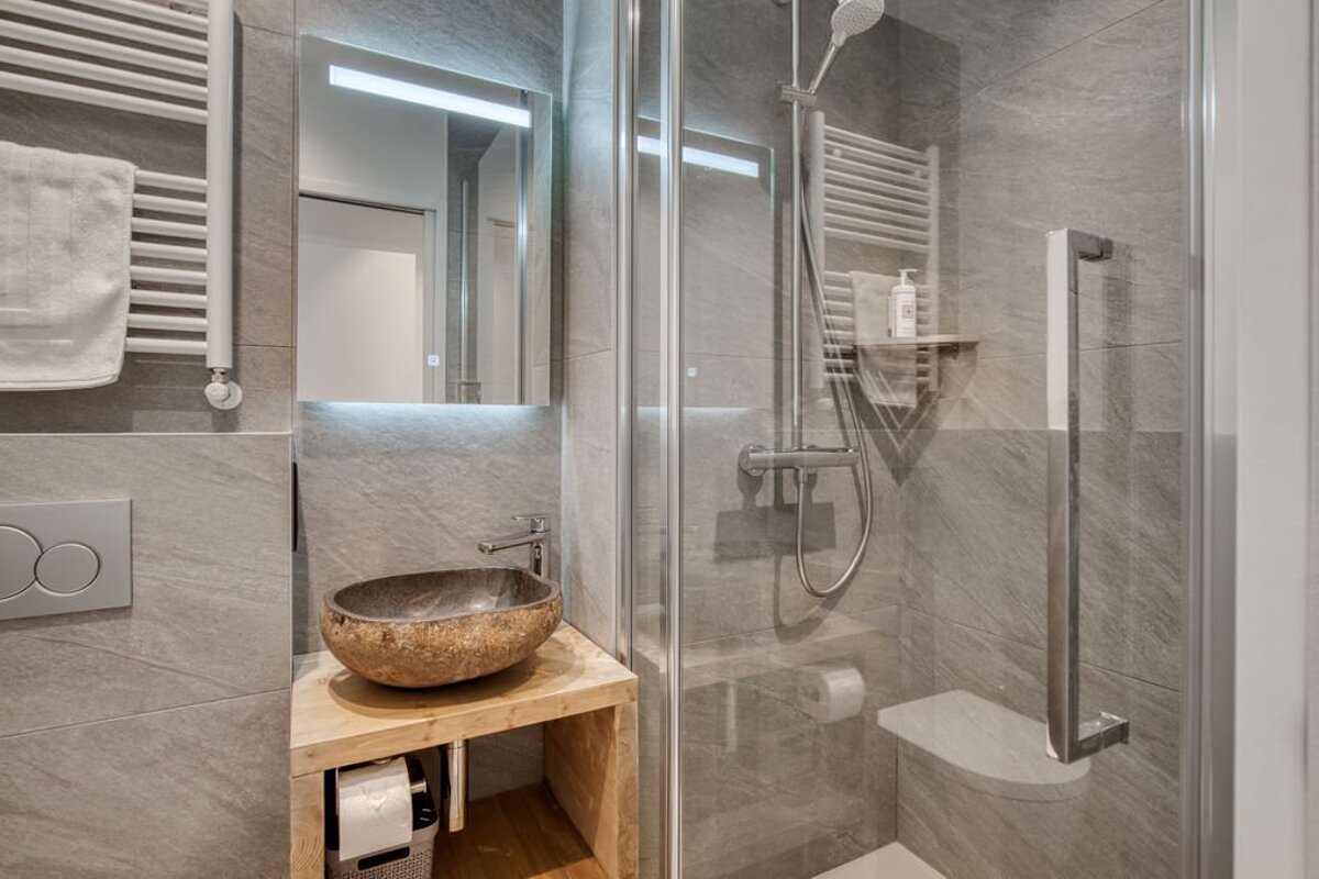 A bathroom with a stone sink and a walk in shower
