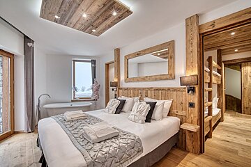 A bedroom with a large bed and a bathtub