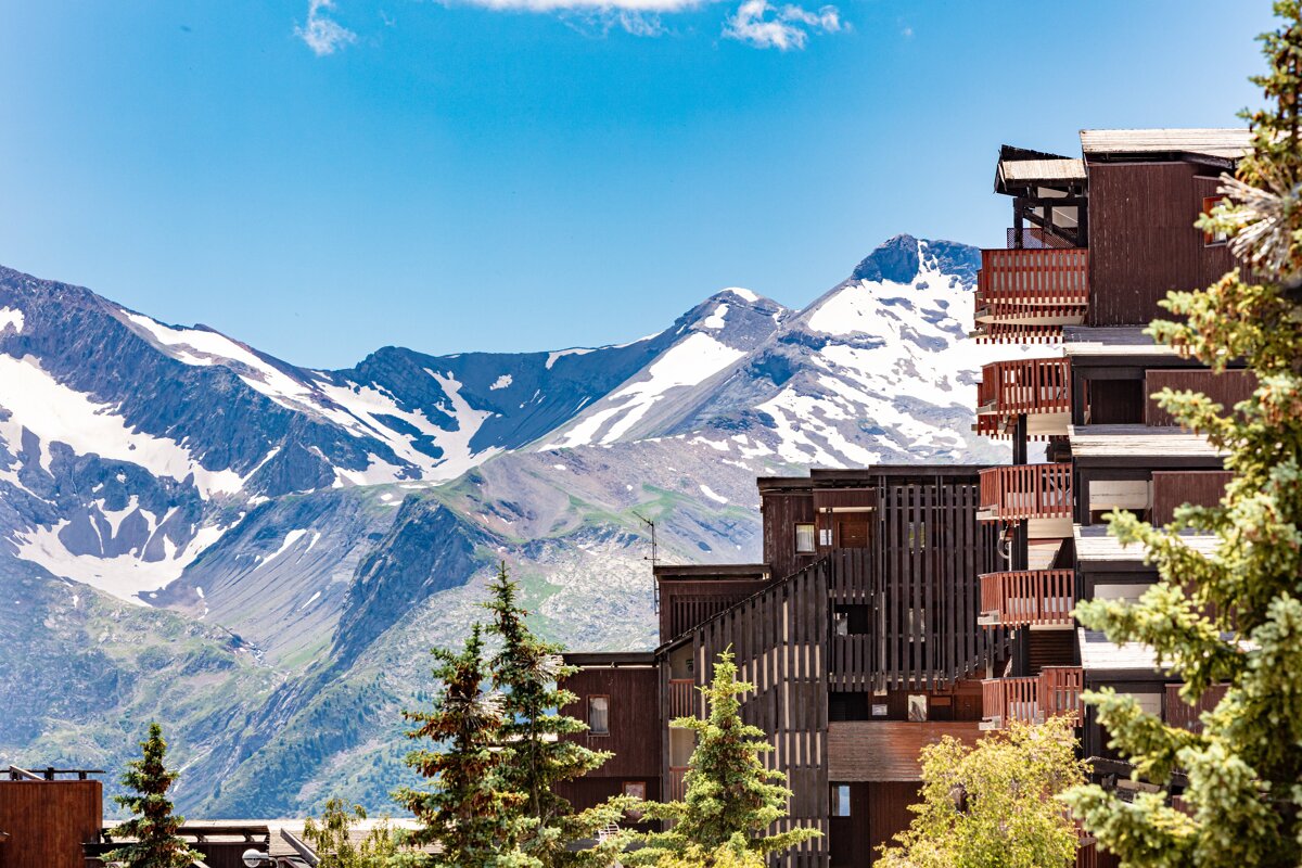A snowy mountain behind a building with balconies