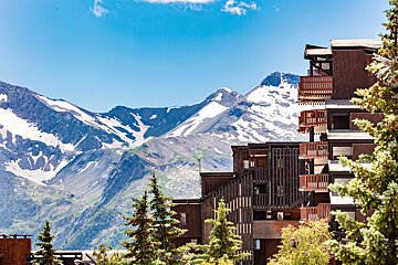 A snowy mountain behind a building with balconies