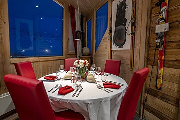 A round table with a white table cloth and red chairs
