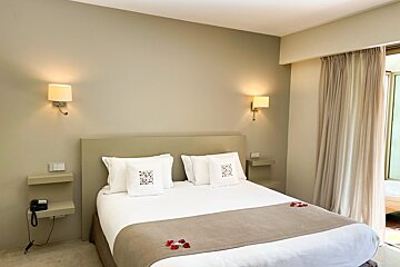 A hotel room with a bed and two lights on the wall