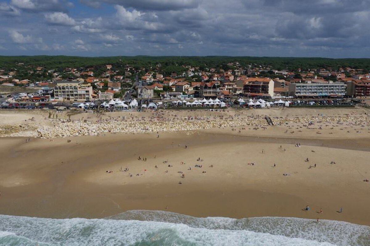 a long beach, town behind and a surf comp going on