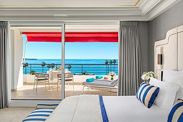 A hotel room with a sliding glass door leading to a balcony overlooking the ocean