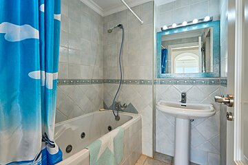 A bathroom with a blue shower curtain and a sink
