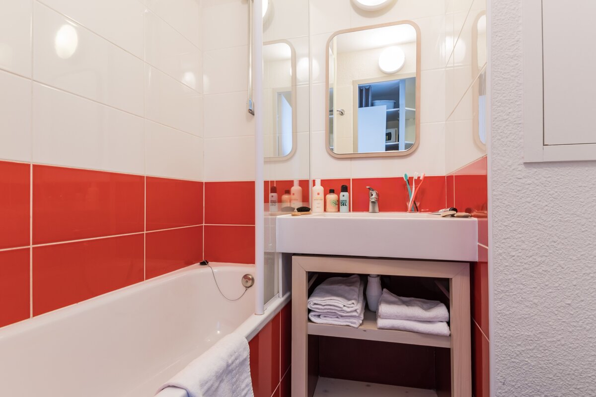 A bathroom with red and white tiles and a sink