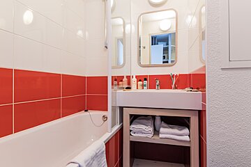 A bathroom with red and white tiles and a sink