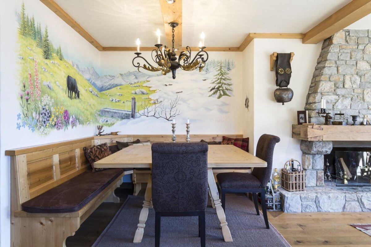 A dining room with a table and chairs and a painting on the wall