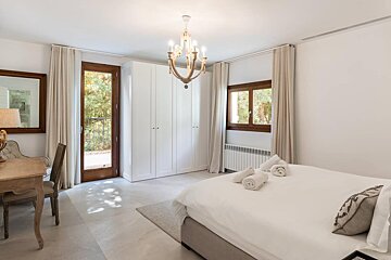 A bedroom with a large bed and a chandelier