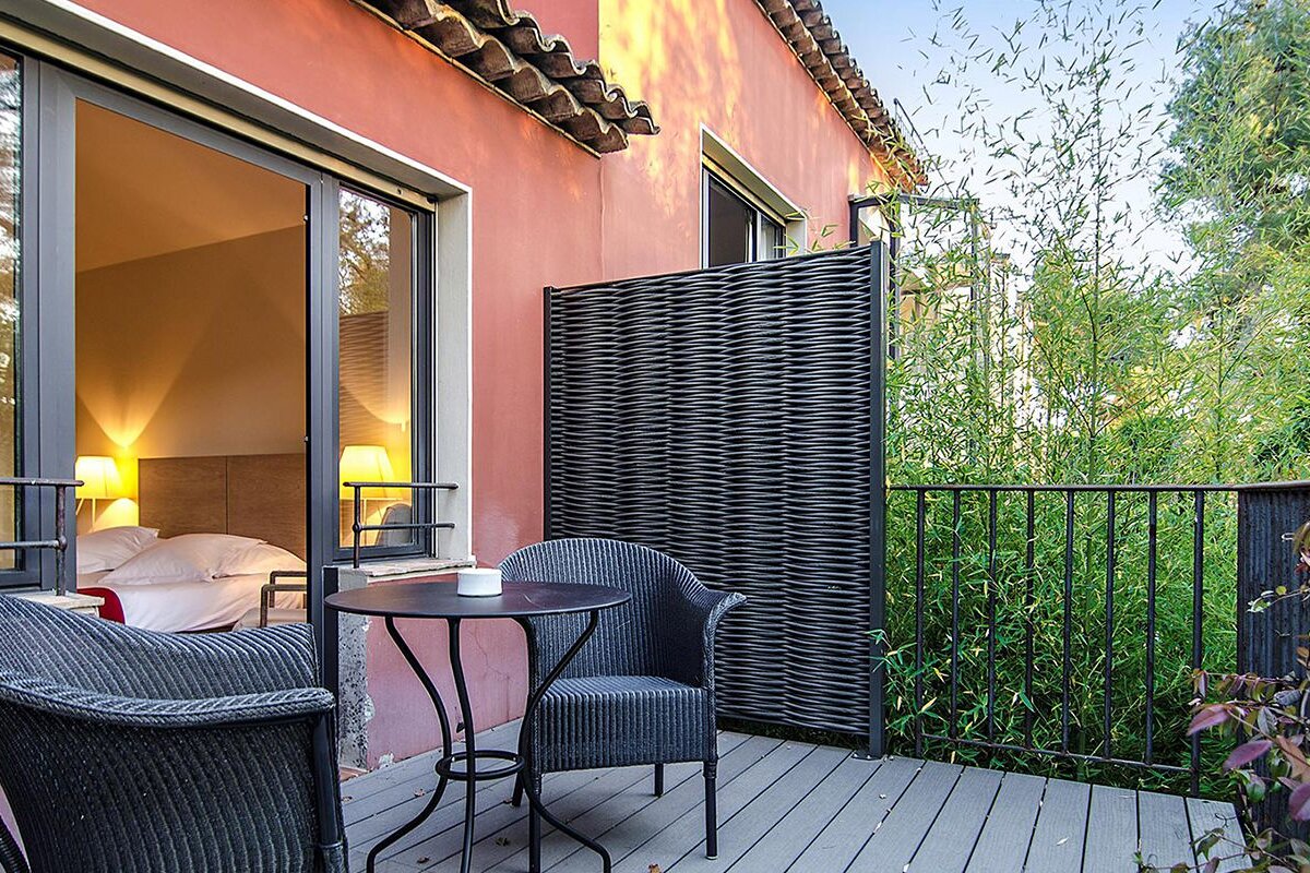 A balcony with two chairs and a table in front of a bedroom