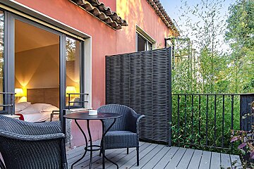 A balcony with two chairs and a table in front of a bedroom