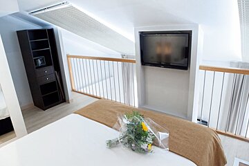 A bedroom with a large flat screen tv on the wall above the bed