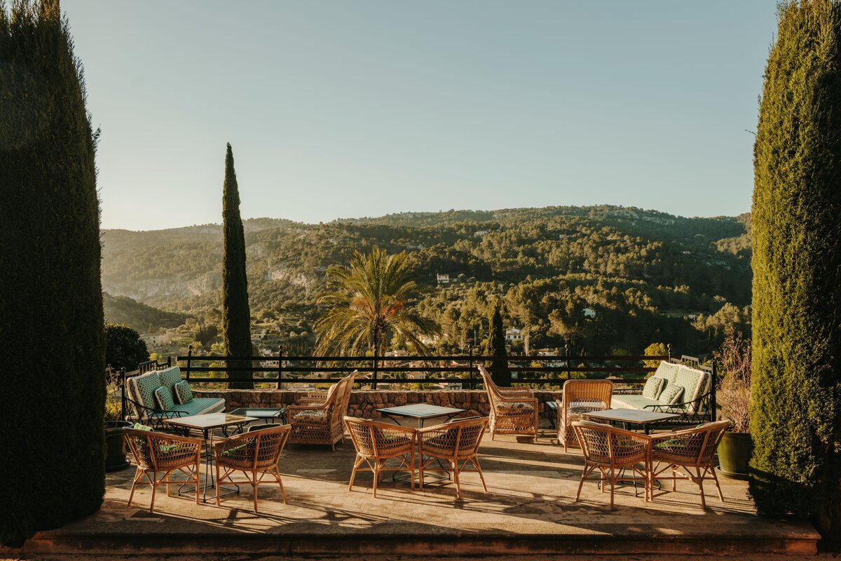 A patio with tables and chairs with a view of the mountains