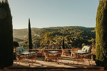 A patio with tables and chairs with a view of the mountains