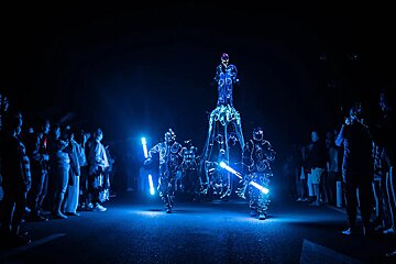 Street show of people in costumes with lights in the dark