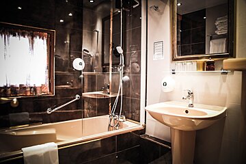 A bathroom with a sink and a bathtub with a sign on the wall that says 