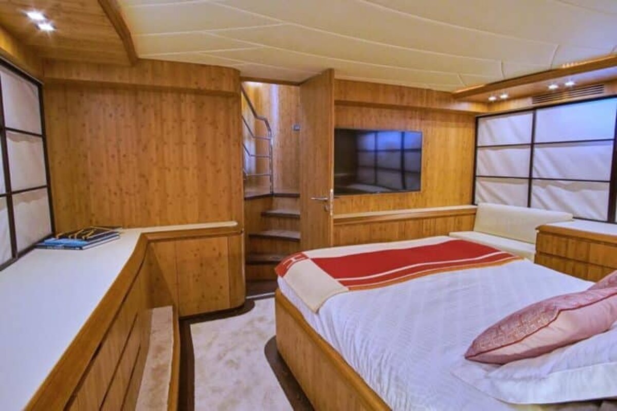 A bedroom on a boat with a large bed and a flat screen tv