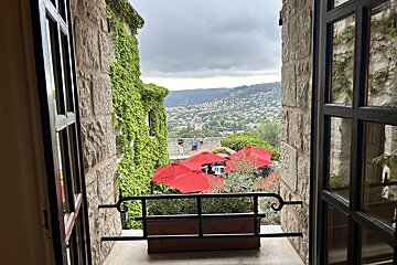 A balcony with red umbrellas and a view of the mountains