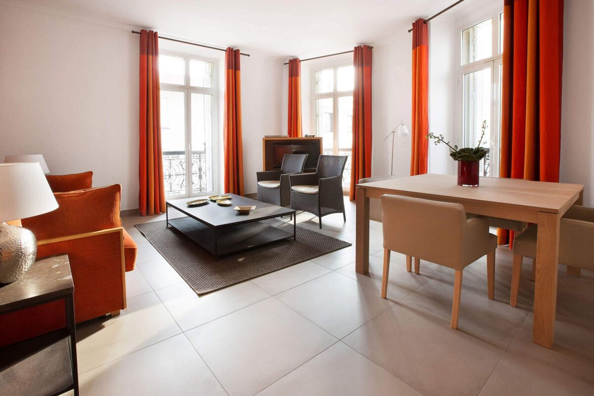 A living room with orange curtains and a table
