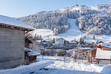 A snowy village with a ski slope in the background
